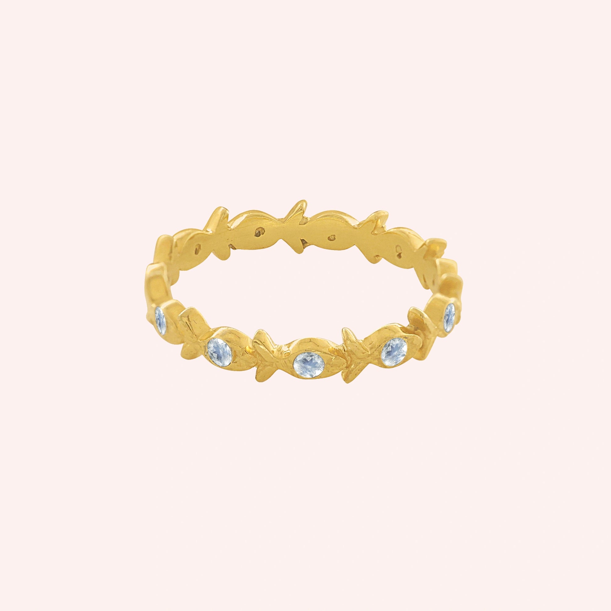 Fish_ring_gold_plated_silver_moonstone_eternity_band_in_front_angle_view_on_solid_pink_background