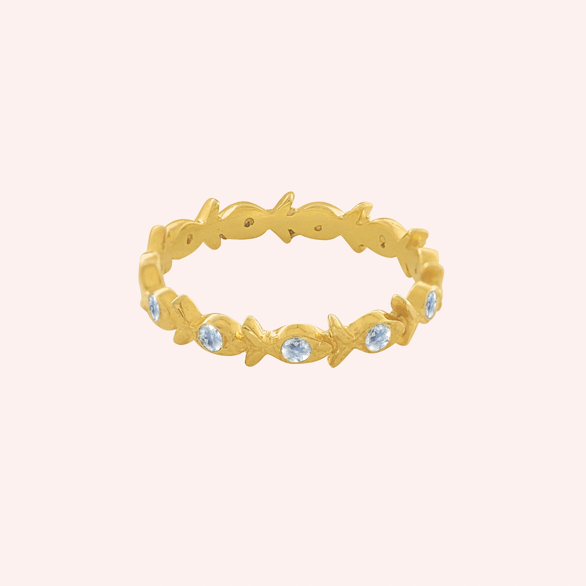 Fish_ring_gold_plated_silver_moonstone_eternity_band_in_front_angle_view_on_solid_pink_background