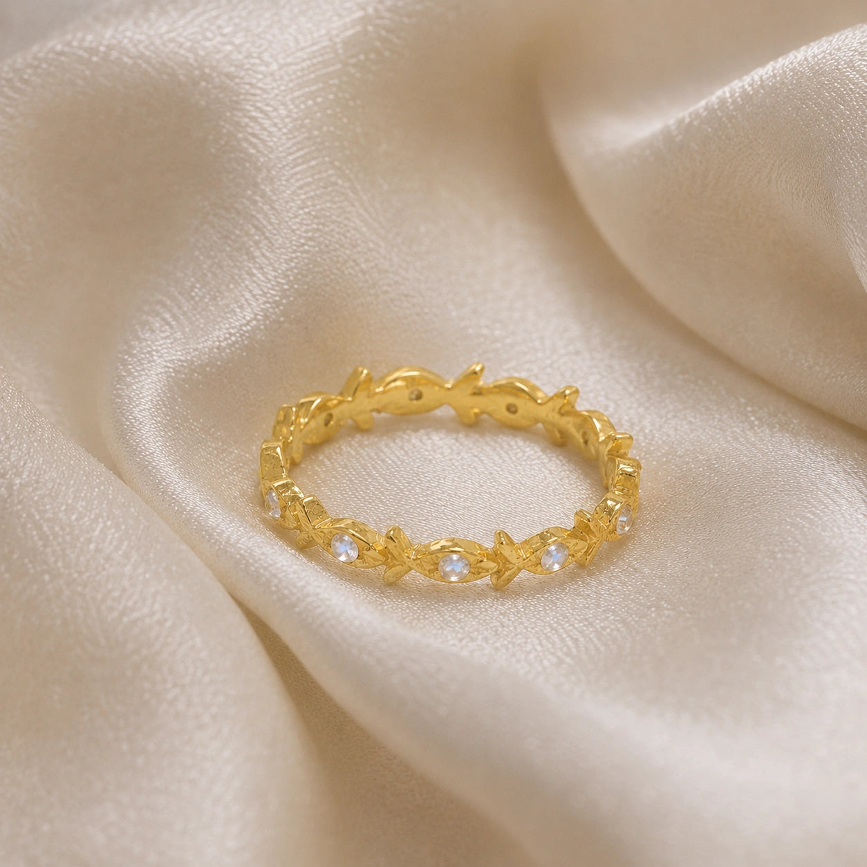 Fish_ring_gold_plated_silver_moonstone_eternity_band_in_front_angle_view_on_soft_fabric_background