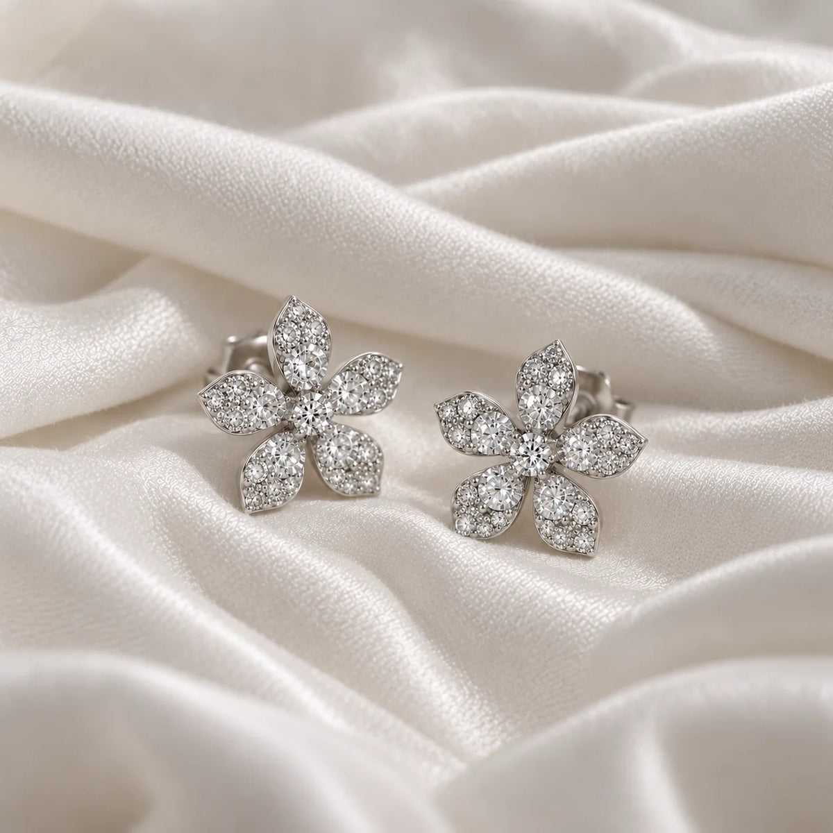 Flower_earrings_in_sterling_silver_with_lab_grown_diamonds_at_side_angle_view_on_soft_fabric_background