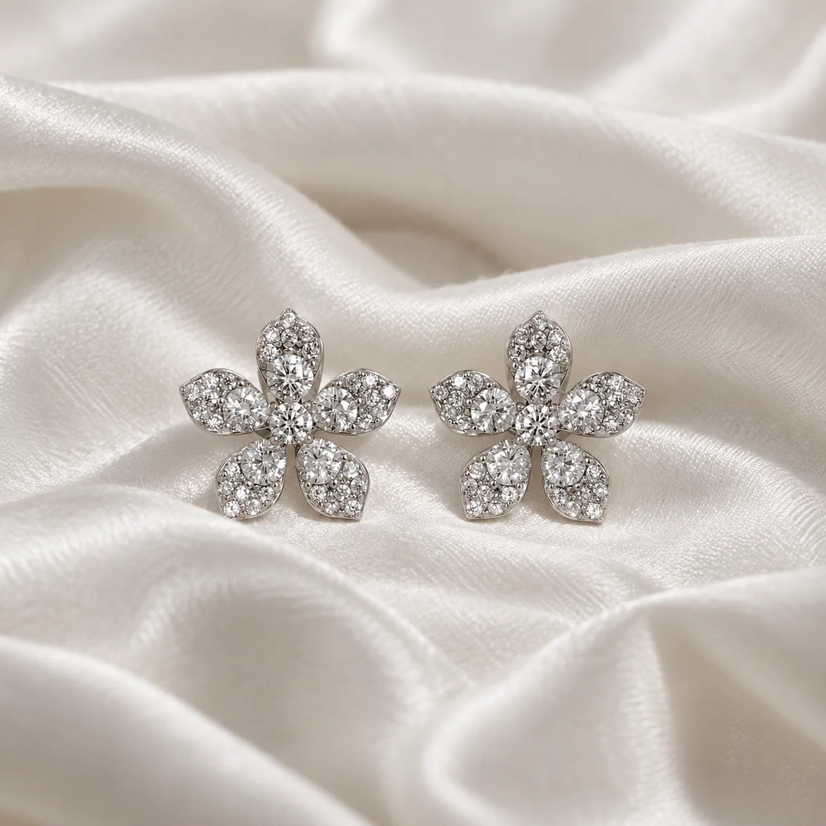 Flower_earrings_in_sterling_silver_with_lab_grown_diamonds_at_front_angle_view_on_soft_fabric_background