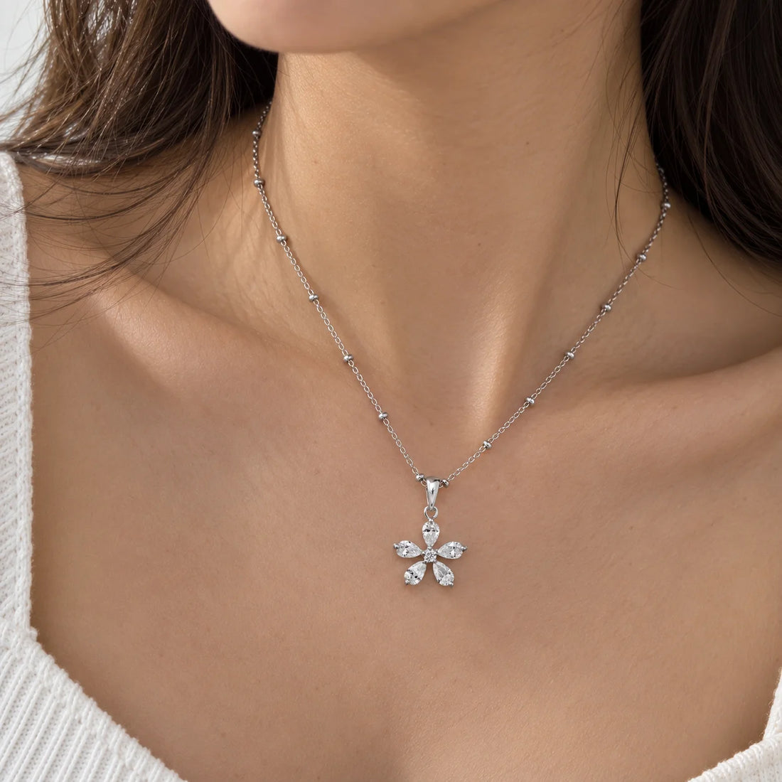 Flower_necklace_in_gold_plated_silver_with_lab_grown_diamonds_at_side_angle_view_on_soft_fabric_background