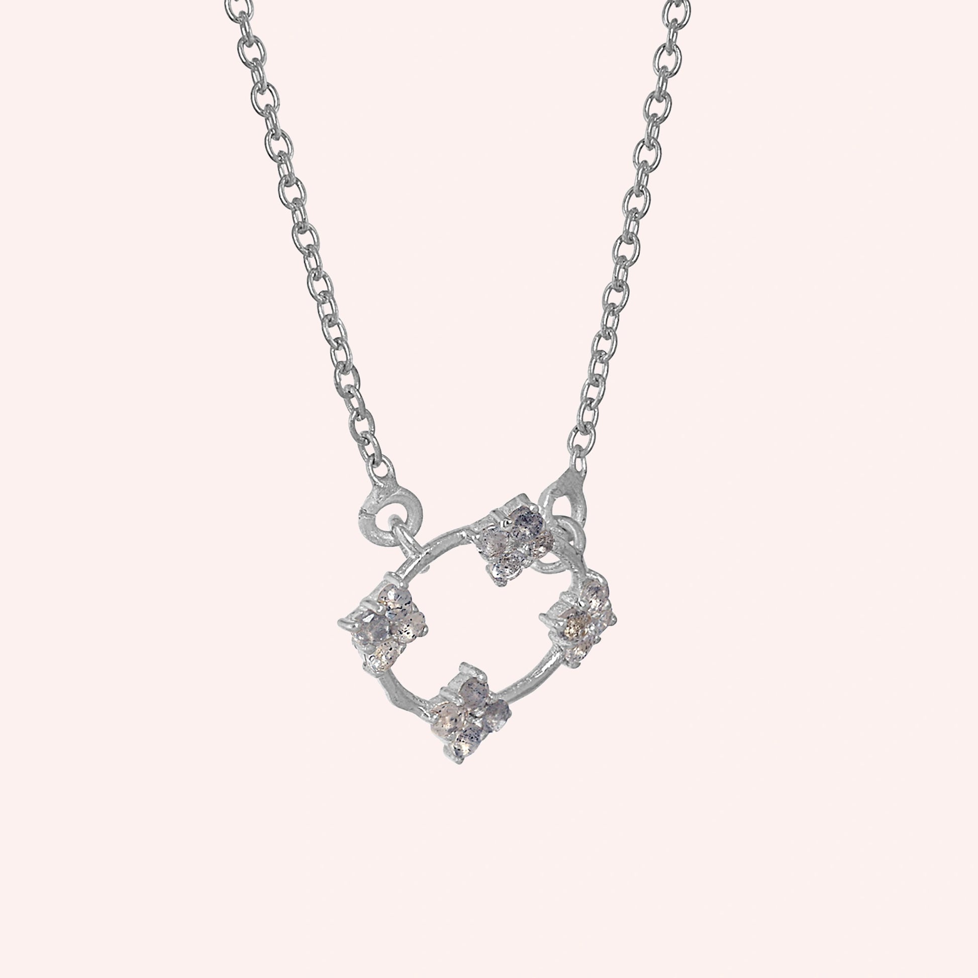 Flower_necklace_with_sterling_silver_chain_and_labradorite_stones_at_slight_angled_view_on_solid_pink_background
