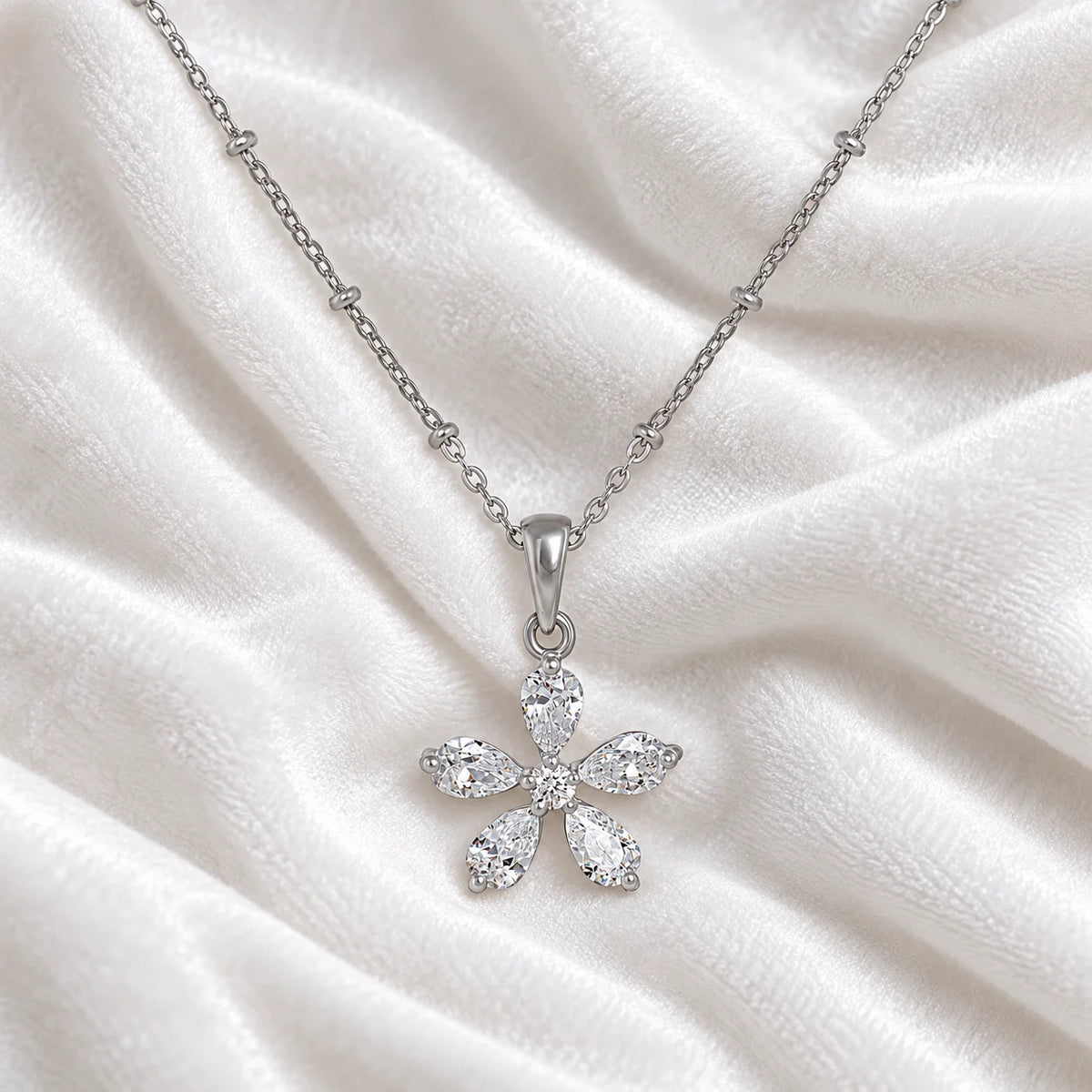 Flower_necklace_in_sterling_silver_with_lab_grown_diamonds_at_front_angle_view_on_soft_fabric_background