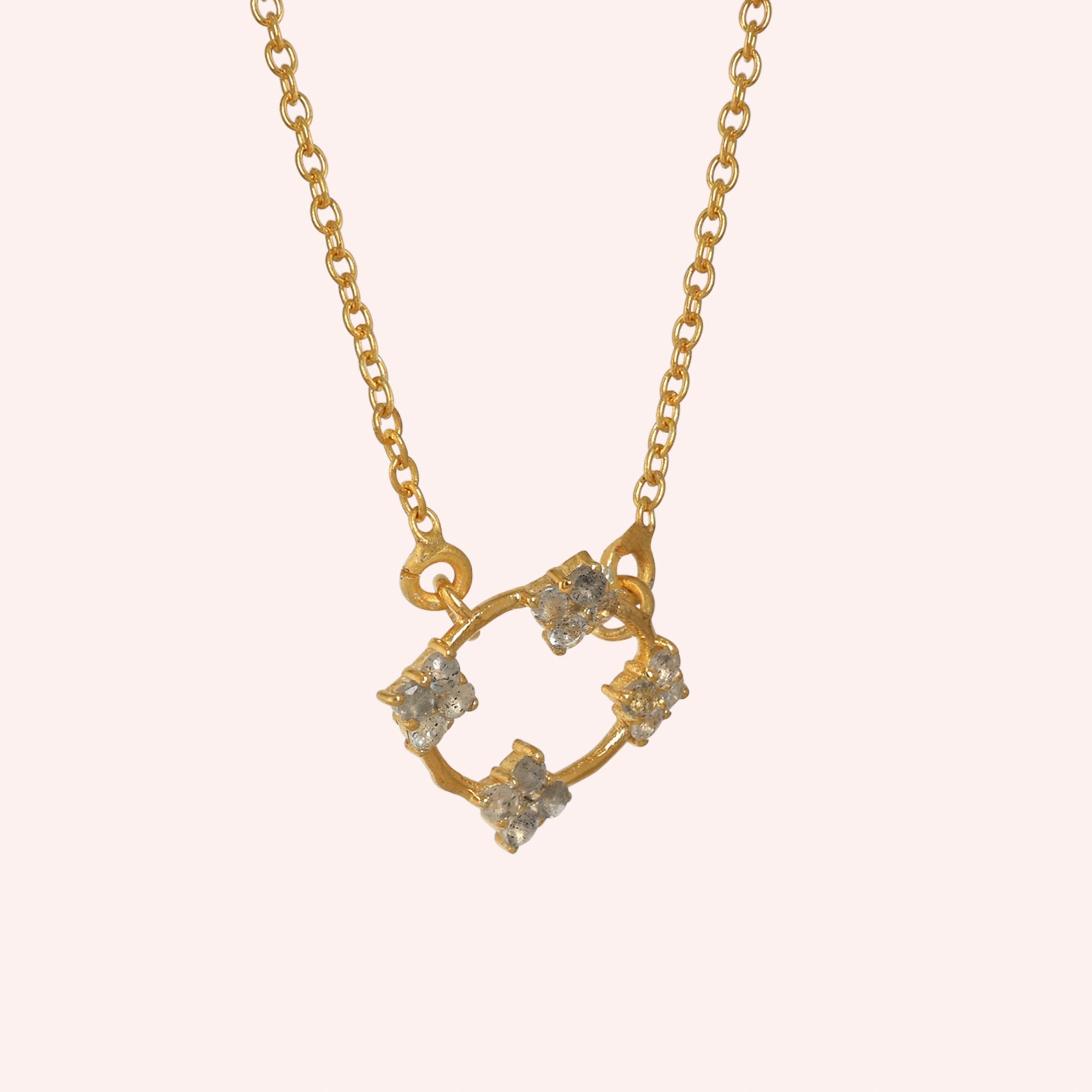 Flower_necklace_with_gold_plated_silver_chain_and_labradorite_stones_at_slight_angled_view_on_solid_pink_background