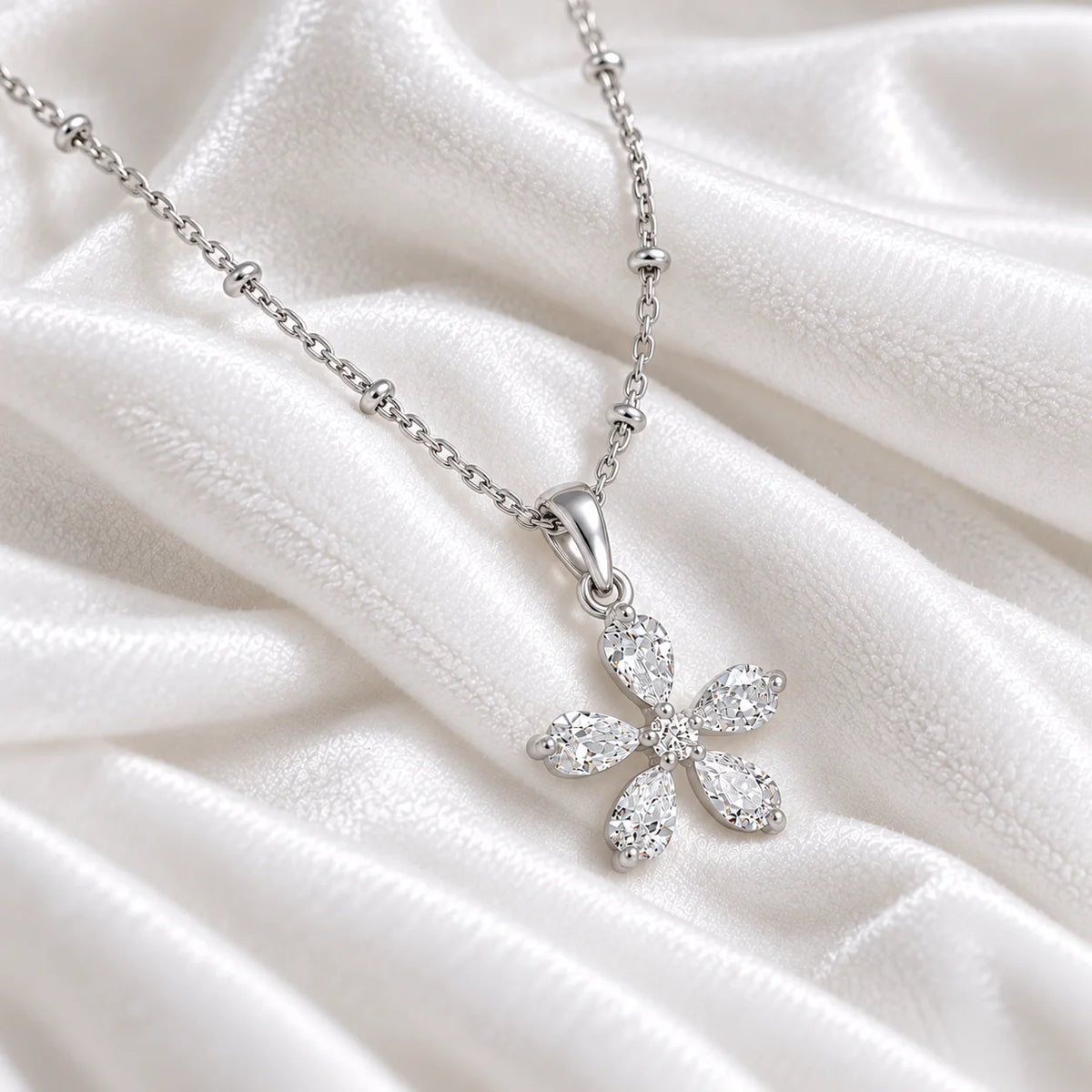 Flower_necklace_in_sterling_silver_with_lab_grown_diamonds_at_side_angle_view_on_soft_fabric_background