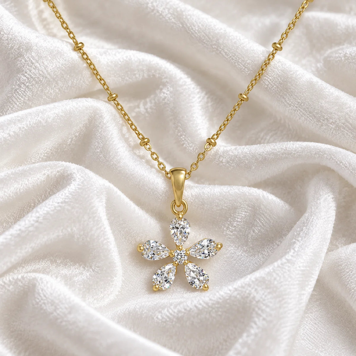 Flower_necklace_in_gold_plated_silver_with_lab_grown_diamonds_at_front_angle_view_on_soft_fabric_background