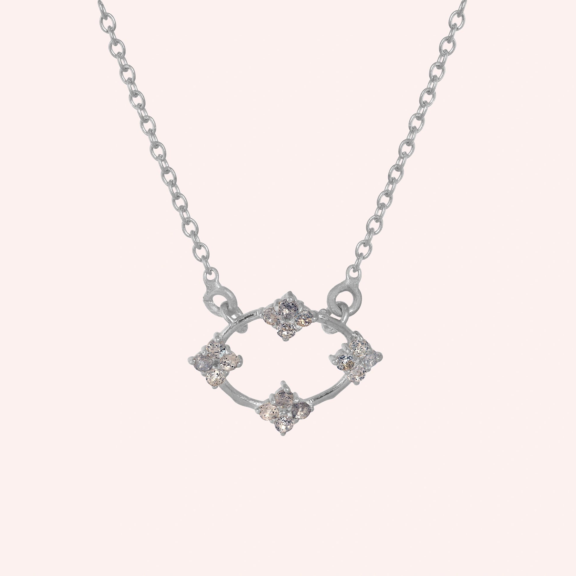 Flower_necklace_with_sterling_silver_chain_and_labradorite_stones_at_front_angle_view_on_solid_pink_background