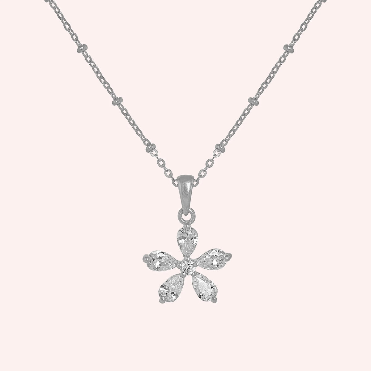 Flower_necklace_in_sterling_silver_with_lab_grown_diamonds_at_front_angle_view_on_solid_pink_background