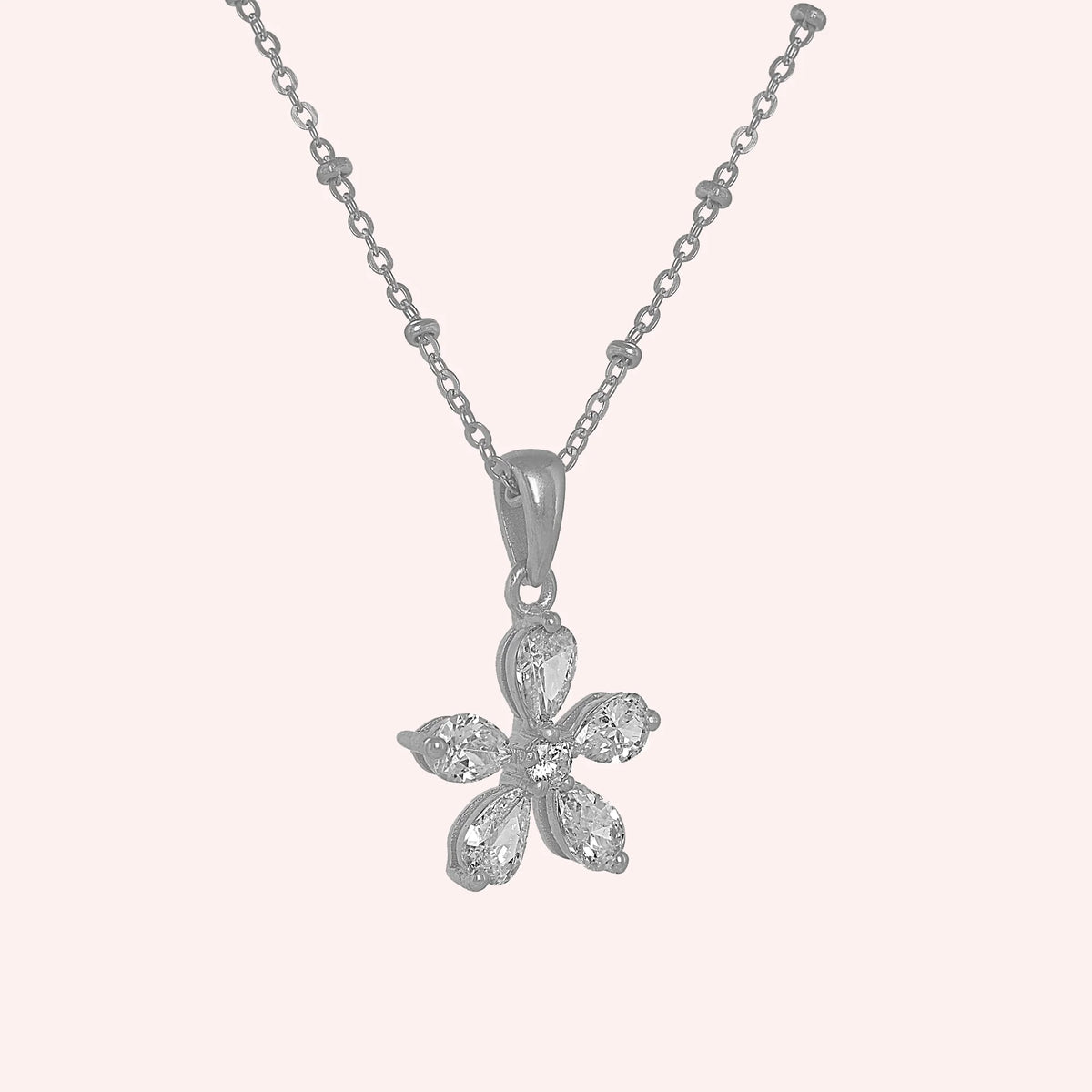 Flower_necklace_in_sterling_silver_with_lab_grown_diamonds_at_side_angle_view_on_solid_pink_background