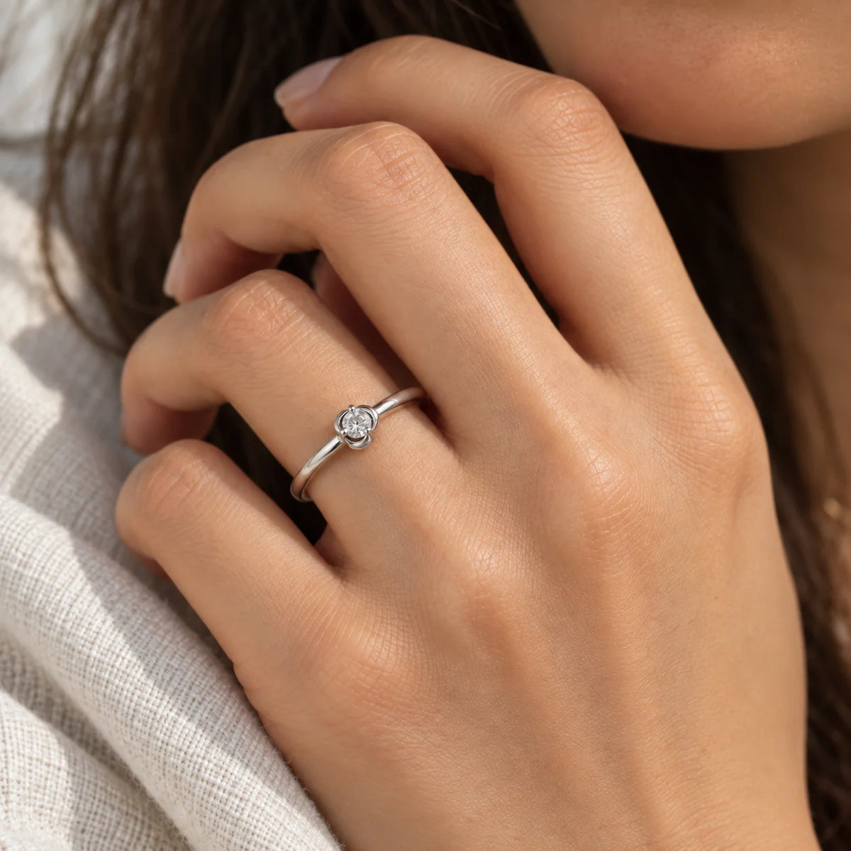 Flower_ring_in_sterling_silver_with_a_round_lab_grown_diamond_at_front_angle_view_on_solid_pink_background