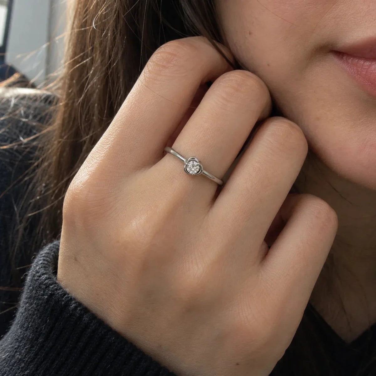 Flower_ring_in_sterling_silver_with_a_small_round_CZ_stone_at_front_angle_view_worn_by_a_model