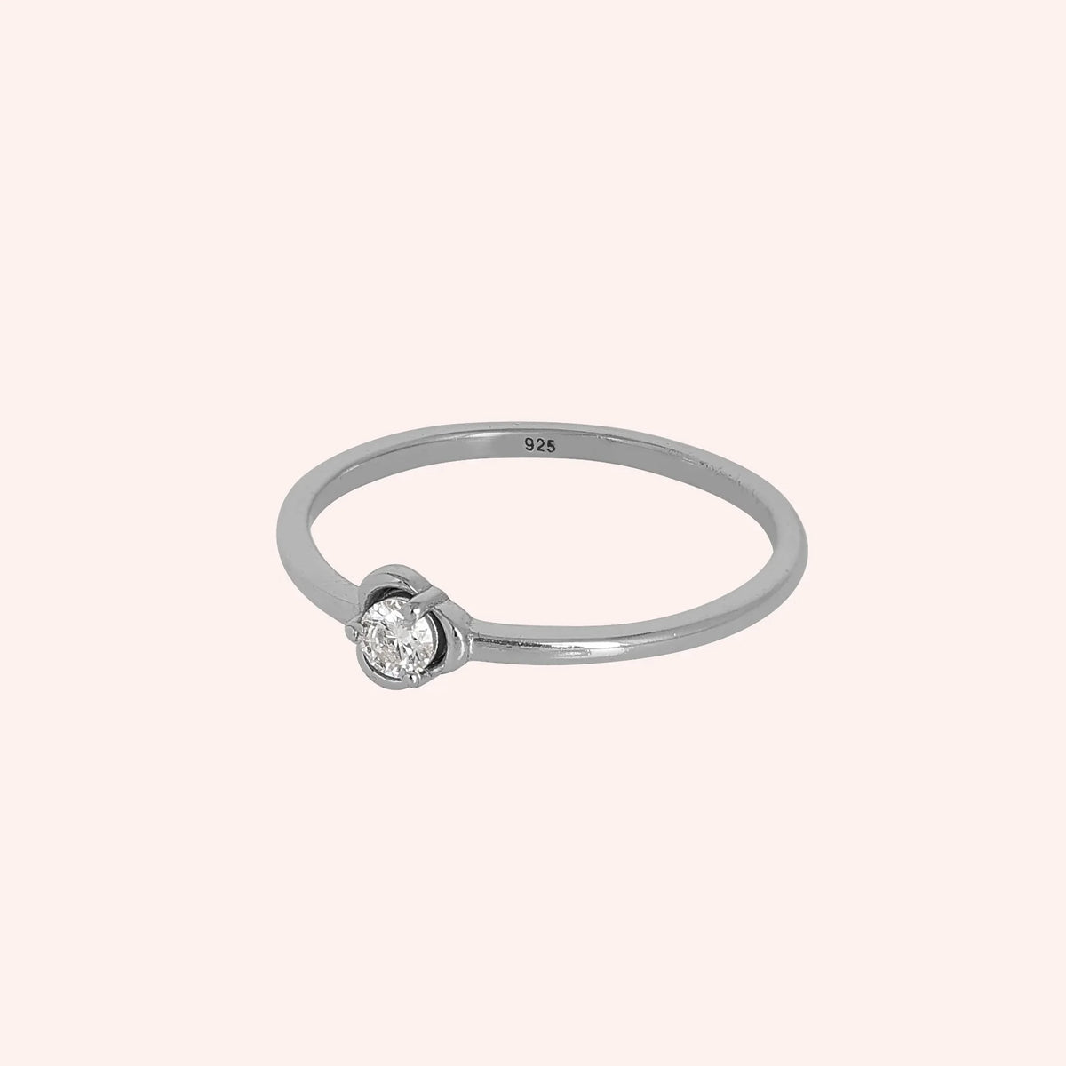 Flower_ring_in_sterling_silver_with_a_small_round_CZ_stone_at_side_angle_view_on_solid_pink_background