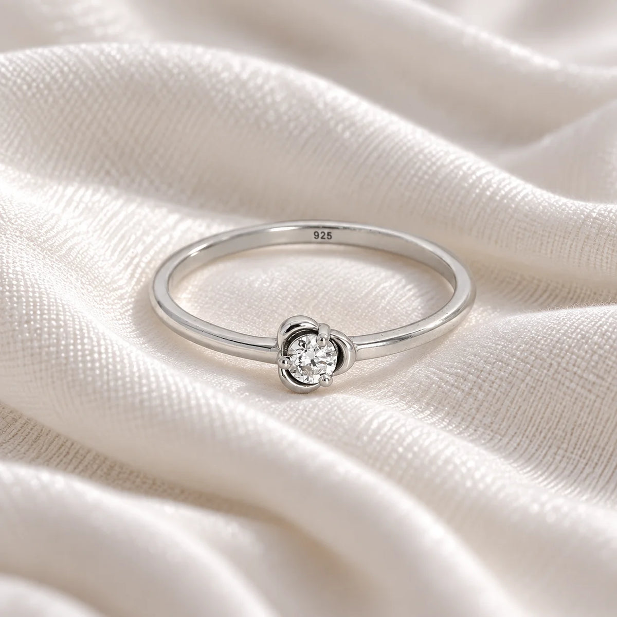 Flower_ring_in_sterling_silver_with_a_round_lab_grown_diamond_at_front_angle_view_on_soft_fabric_background