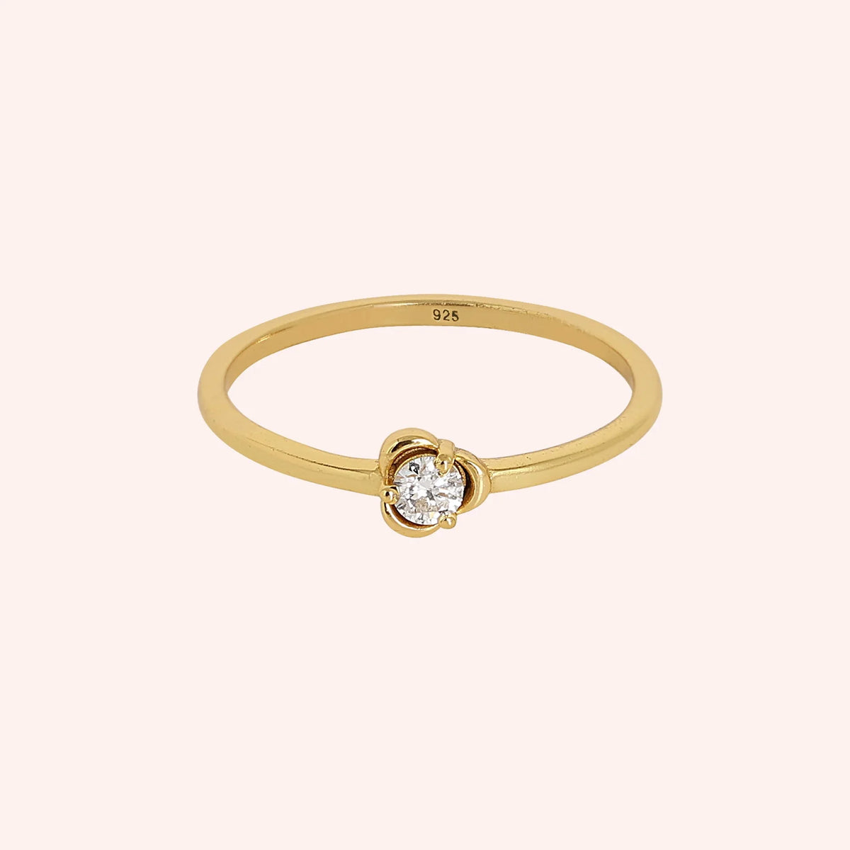 Flower_ring_in_gold_plated_silver_with_a_small_round_CZ_stone_at_front_angle_view_on_solid_pink_background