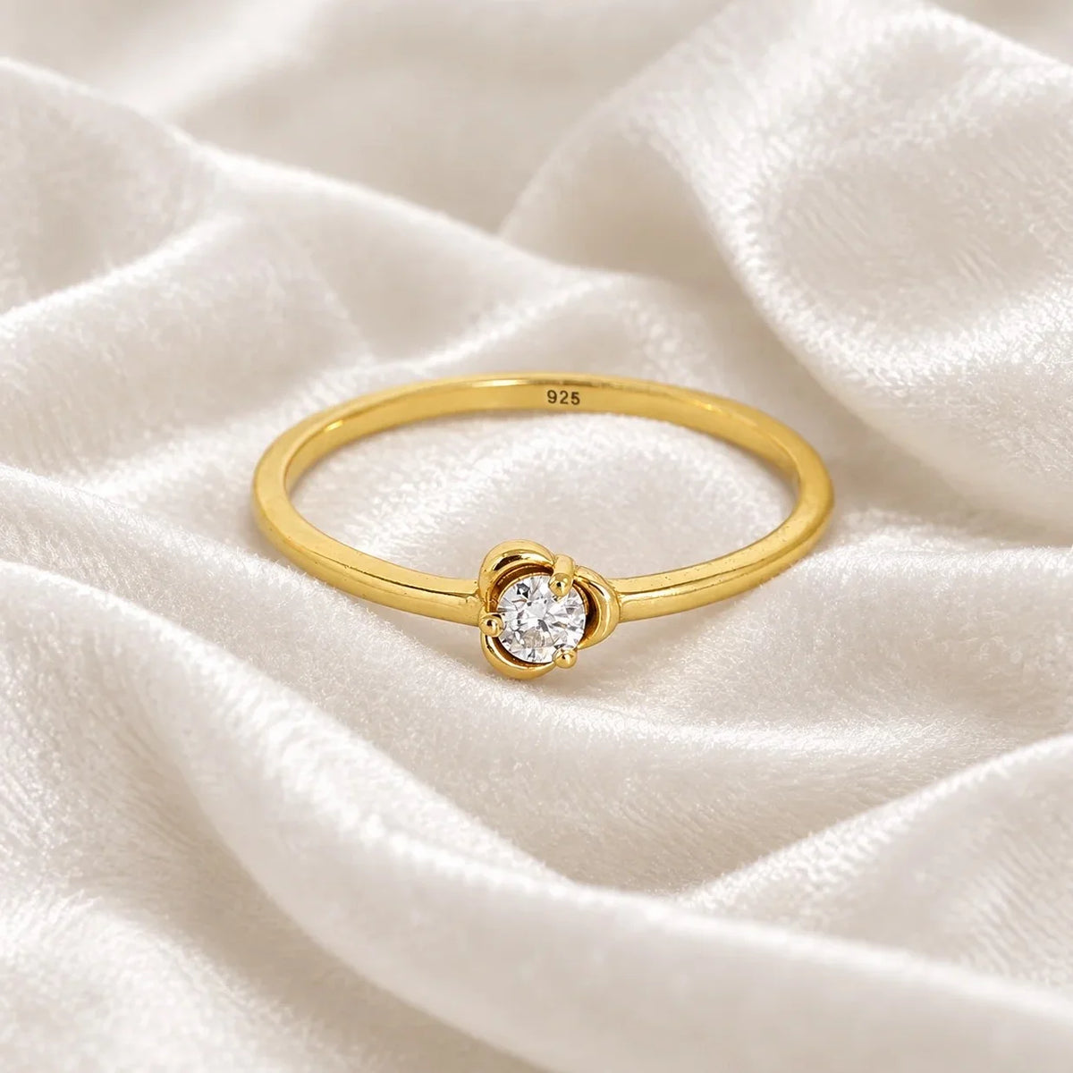 Flower_ring_in_gold_plated_silver_with_a_small_round_CZ_stone_at_front_angle_view_on_soft_fabric_background