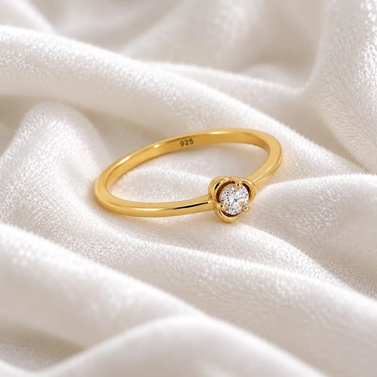 Flower_ring_in_gold_plated_silver_with_a_small_round_CZ_stone_at_side_angle_view_on_soft_fabric_background