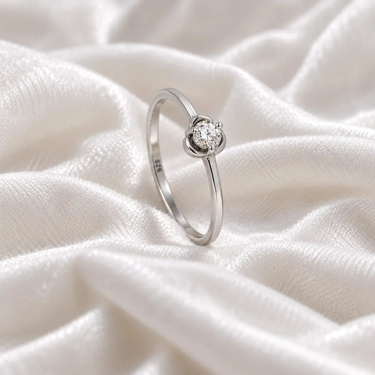 Flower_ring_in_sterling_silver_with_a_small_round_CZ_stone_at_side_angle_view_on_soft_fabric_background