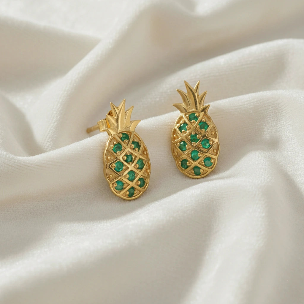 Fruit-earrings-pineapple-design-with-green-gemstones-gold-plated-silver-slight-angled-view-on-white-satin-background