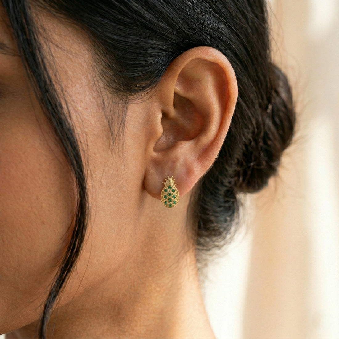 Fruit-earrings-pineapple-design-with-green-gemstones-gold-plated-silver-slight-angled-view-on-white-satin-background