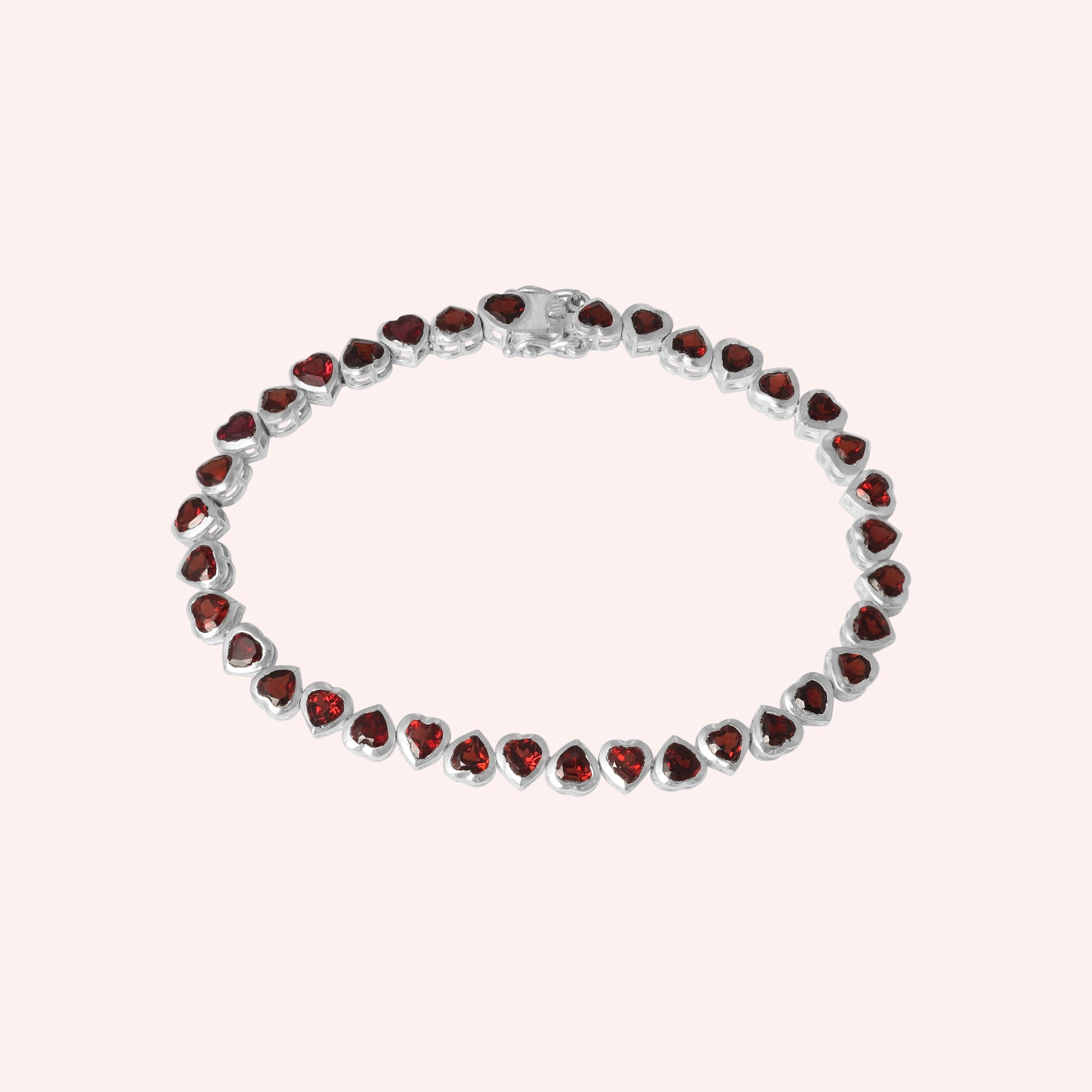 Sterling silver garnet bracelet with heart shaped red stones on a minimal light pink background straight on view.