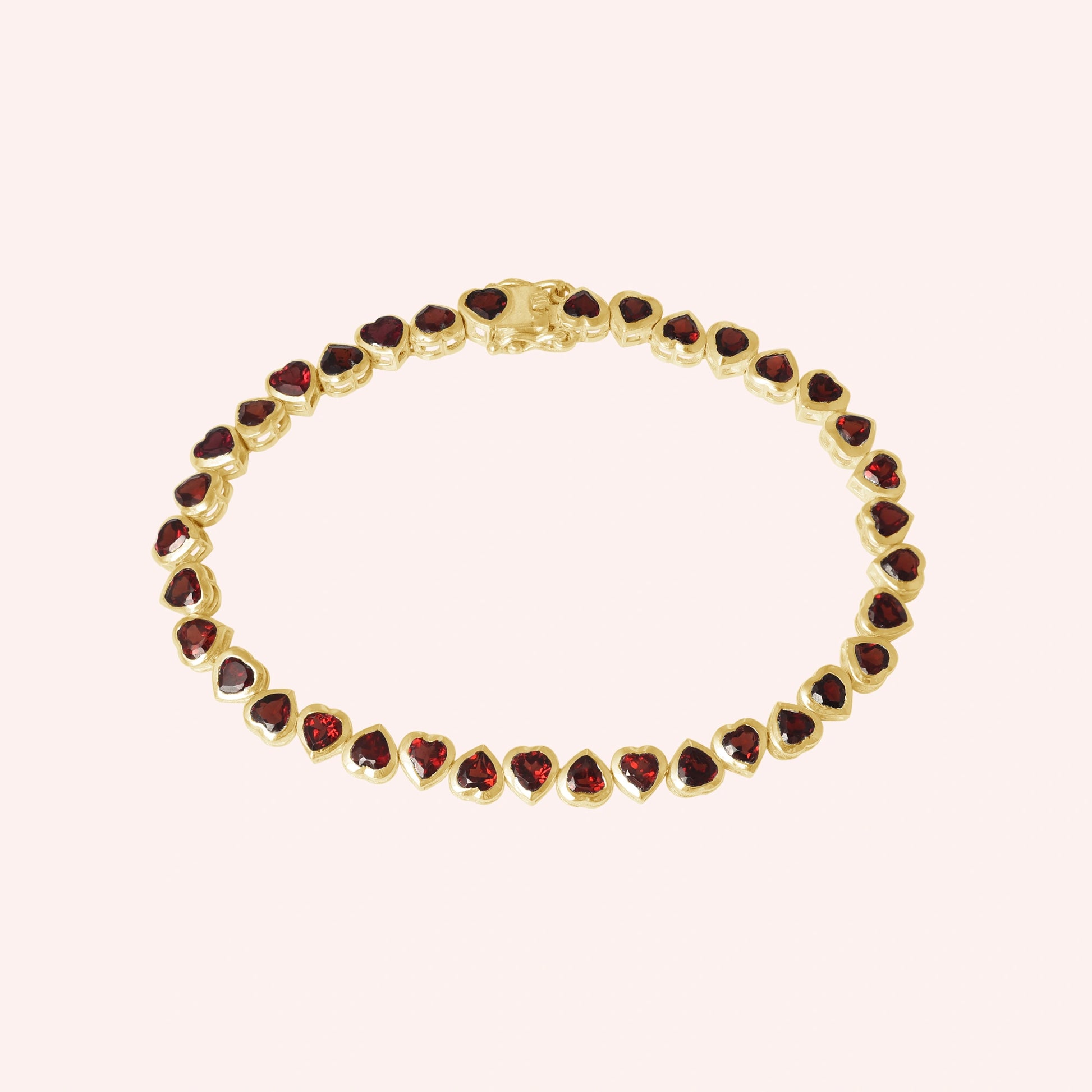 Gold-plated garnet bracelet with heart shaped red stones on a minimal light pink background viewed straight on for product detail.