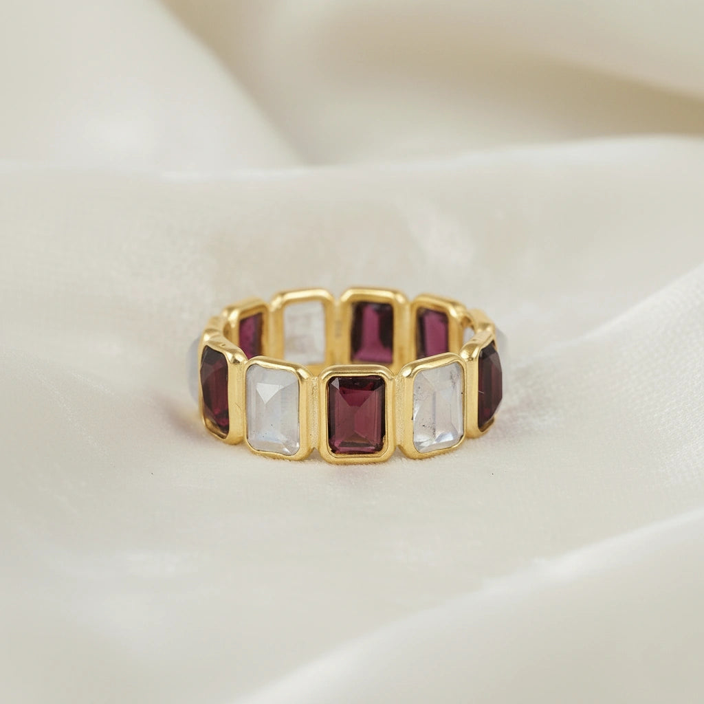Gold-plated Garnet ring band featuring rectangular moonstone and rich red Garnet gems on white velvet fabric front view.