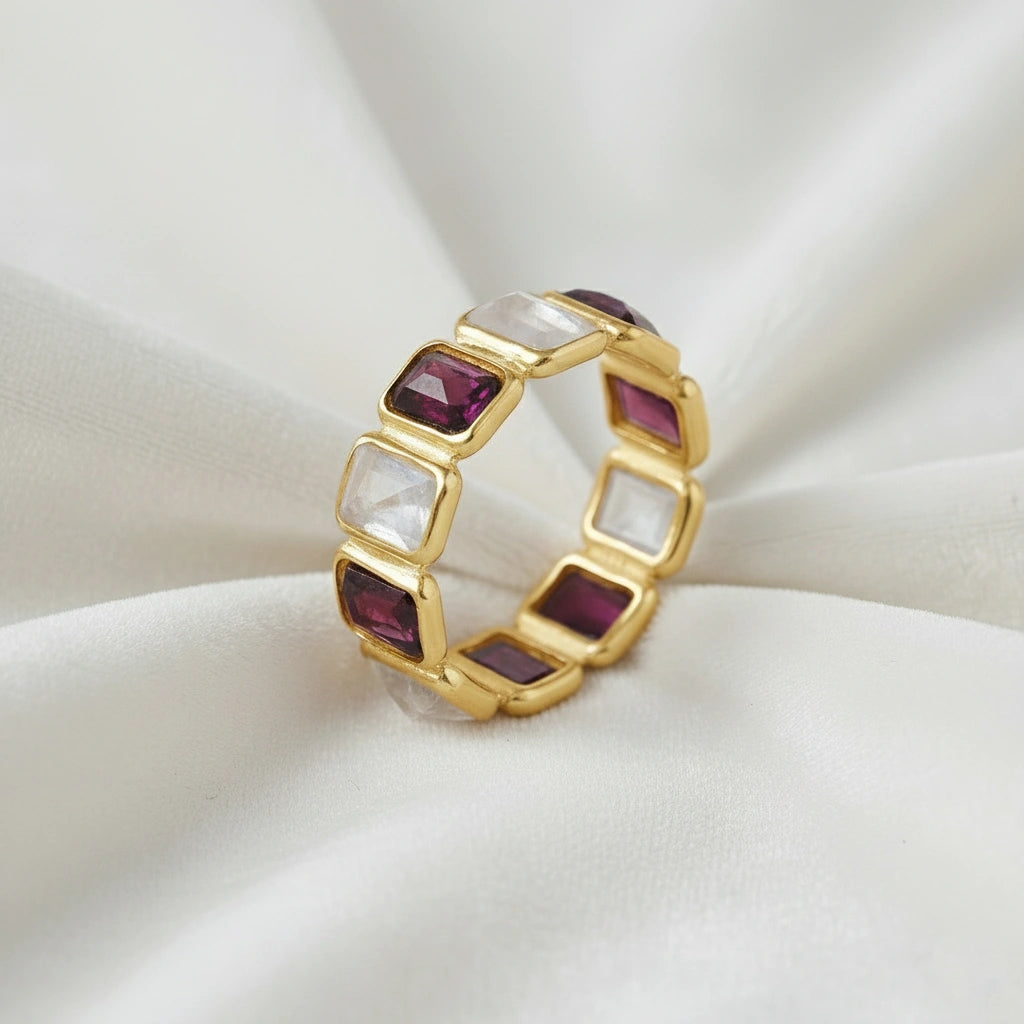 Gold-plated Garnet ring band featuring rectangular moonstone and rich red Garnet gems on a white velvet fabric side angle.