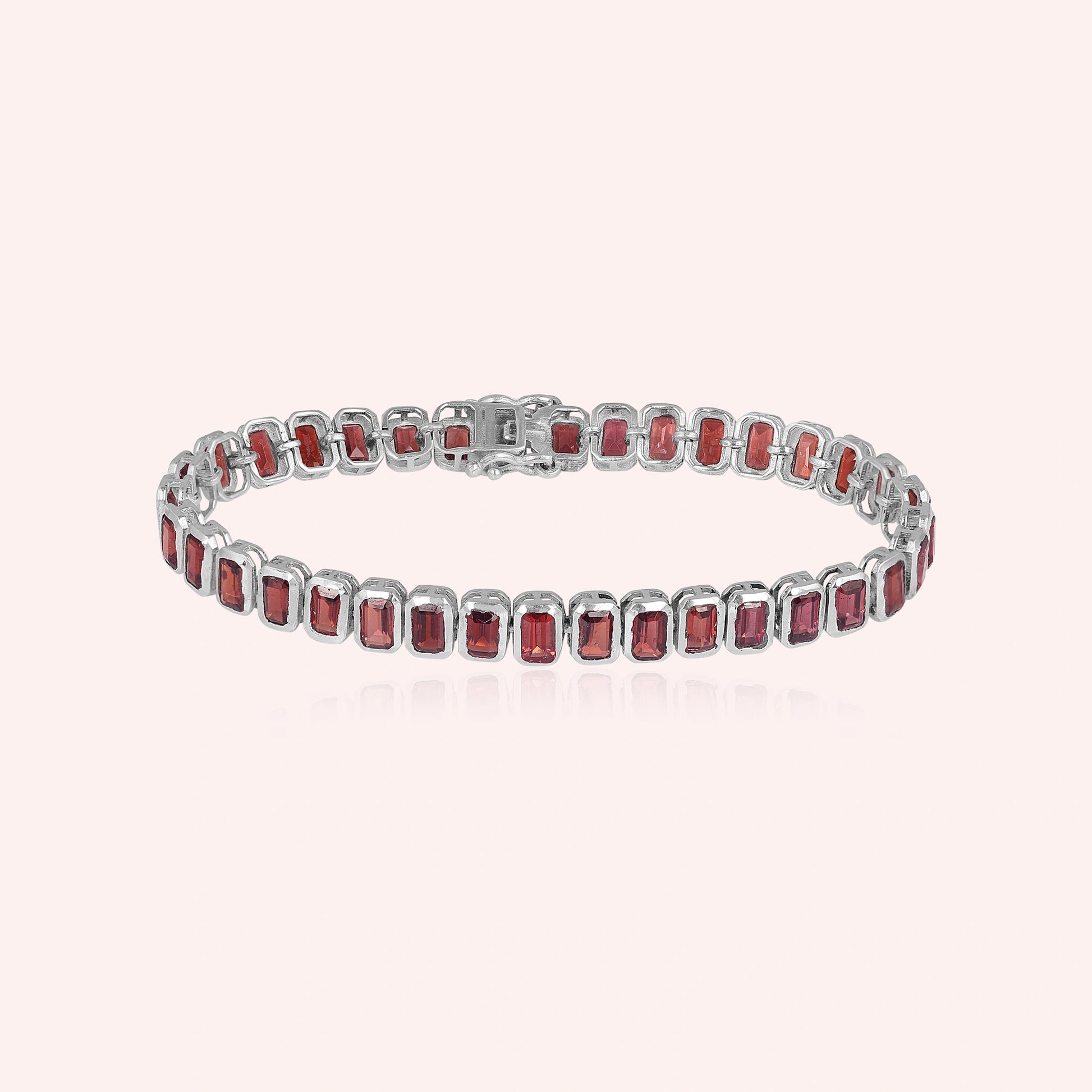 sterling silver tennis bracelet with rectangular red garnet gemstones on a pink background studio shot top down angle