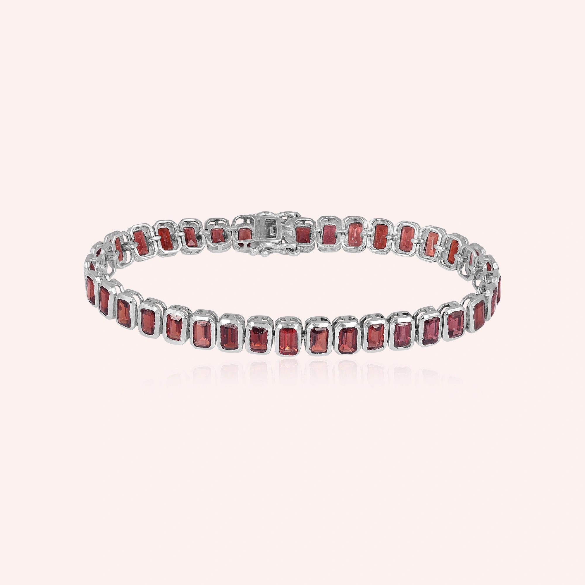 sterling silver tennis bracelet with rectangular red garnet gemstones on a pink background studio shot top down angle