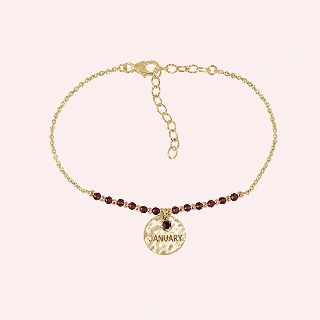 Birthstone_bracelet_in_gold_plated_silver_with_January_charm_and_garnet_beads_on_fine_chain_on_solid_pink_background