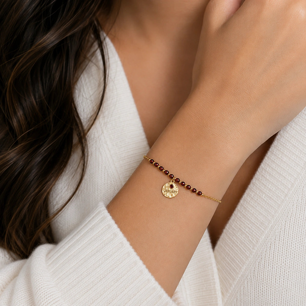 Birthstone_bracelet_in_gold_plated_silver_with_January_charm_and_garnet_beads_worn_by_a_model