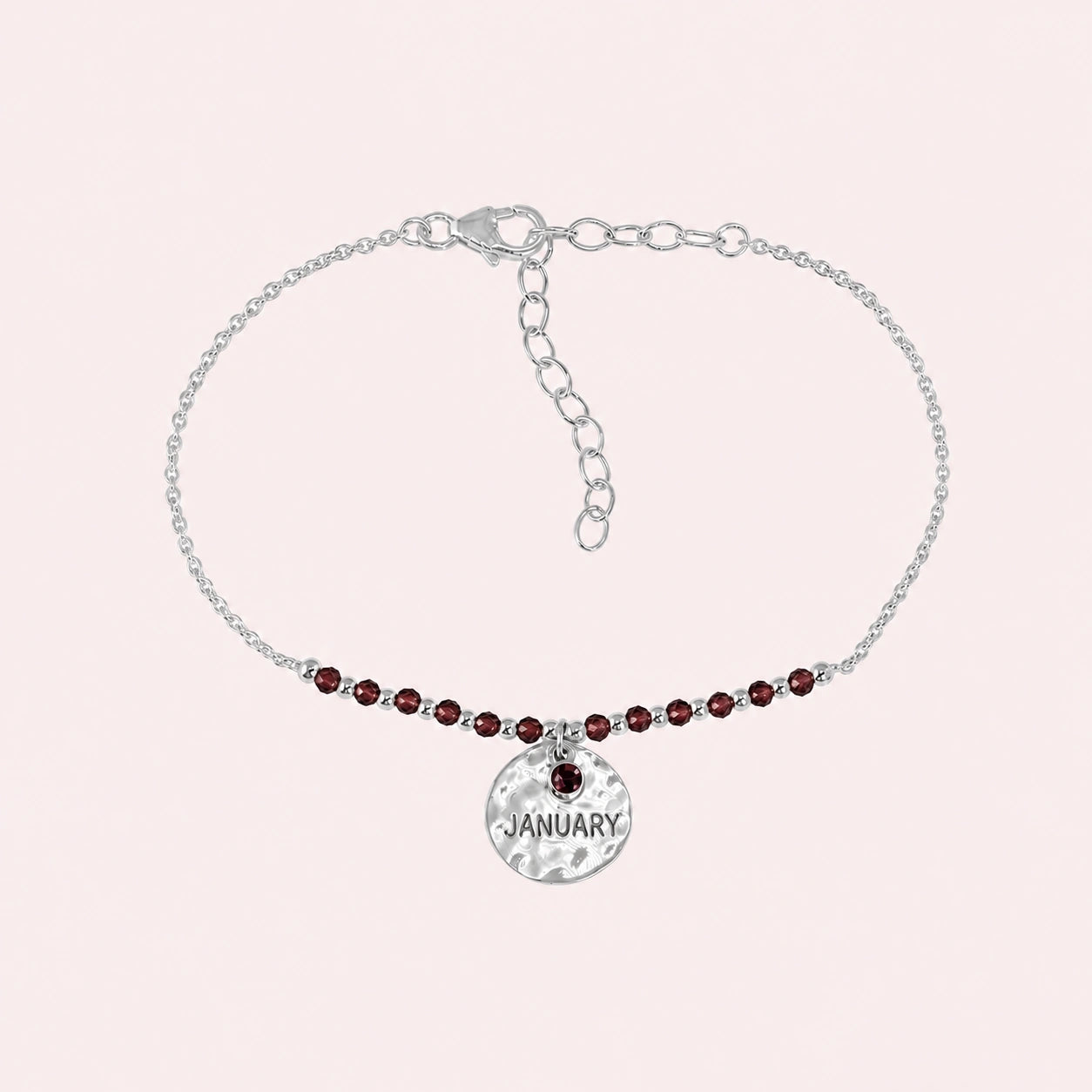Birthstone_bracelet_in_sterling_silver_with_January_charm_and_garnet_beads_on_fine_chain_on_solid_pink_background