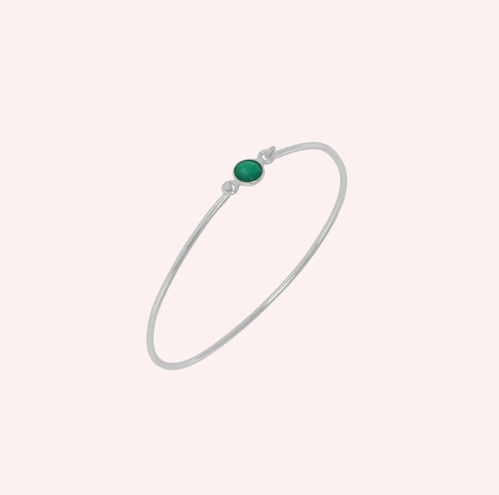 Gemstone_bracelet_in_sterling_silver_with_a_round_green_onyx_stone_at_slight_angle_view_on_solid_pink_background
