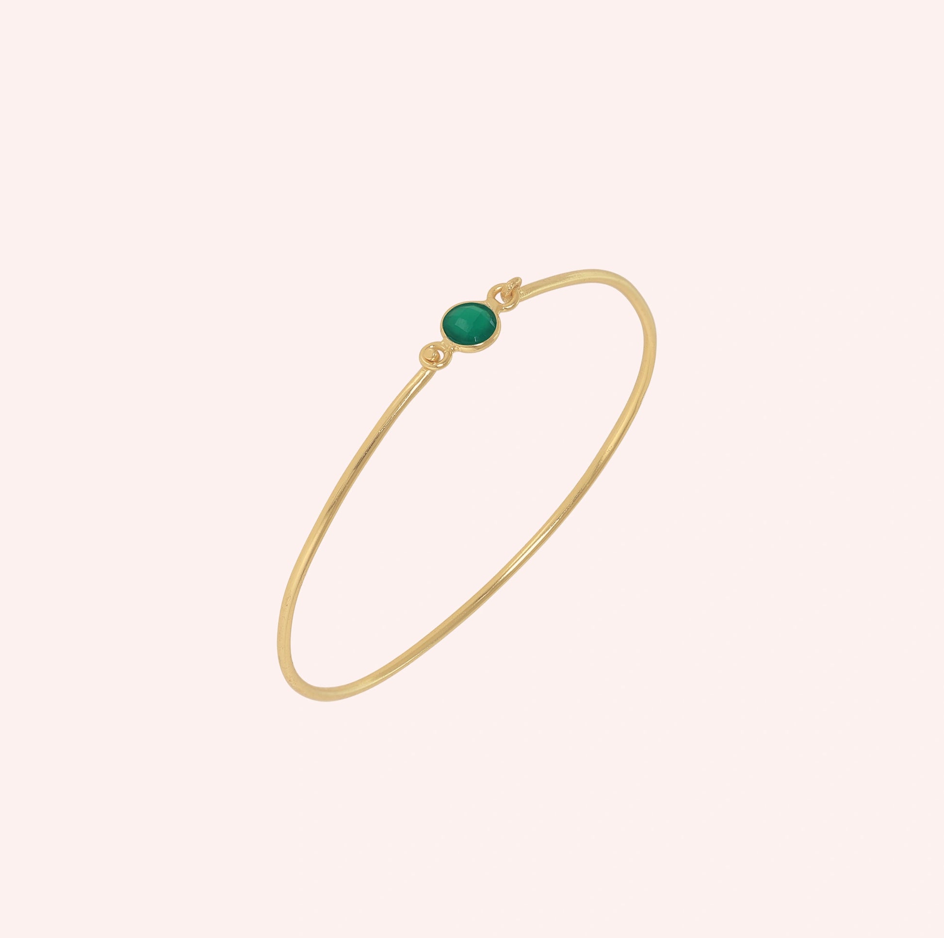 Gemstone_bracelet_in_gold_plated_silver_with_a_round_green_onyx_stone_at_slight_angle_view_on_solid_pink_background