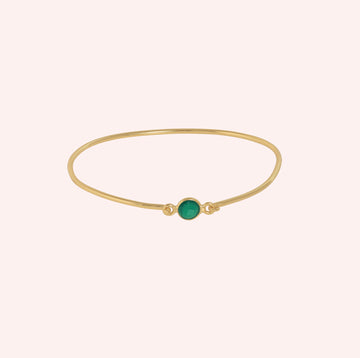 Gemstone_bracelet_in_gold_plated_silver_with_a_round_green_onyx_stone_at_front_angle_view_on_solid_pink_background