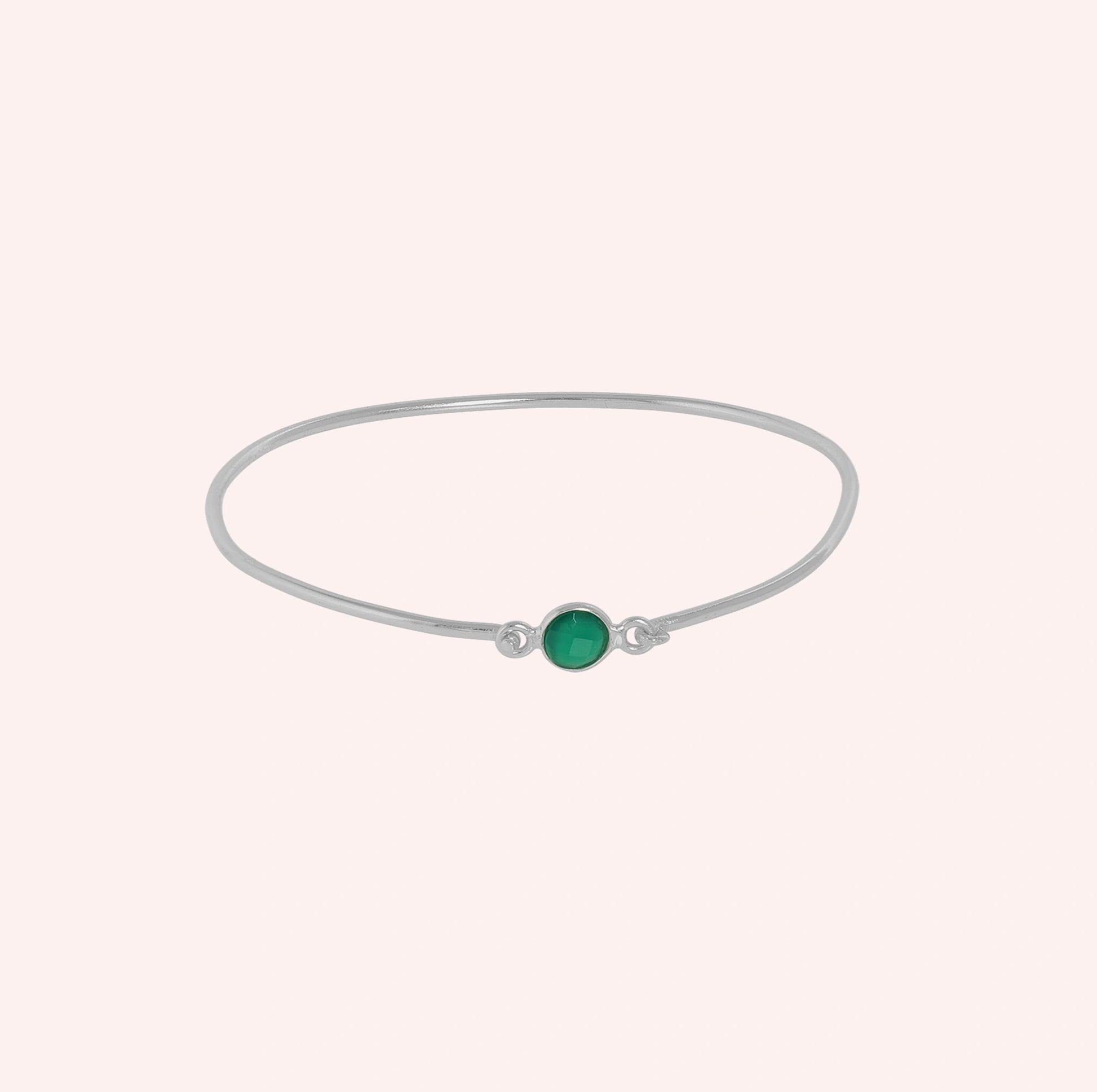 Gemstone_bracelet_in_sterling_silver_with_a_round_green_onyx_stone_at_front_angle_view_on_solid_pink_background