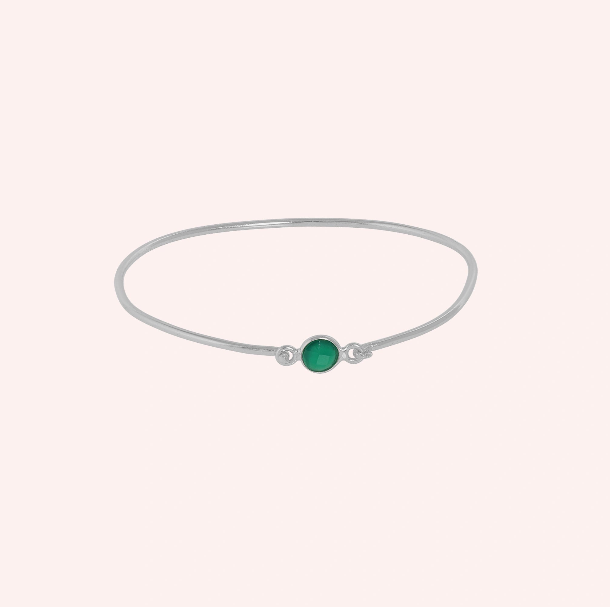 Gemstone_bracelet_in_sterling_silver_with_a_round_green_onyx_stone_at_front_angle_view_on_solid_pink_background