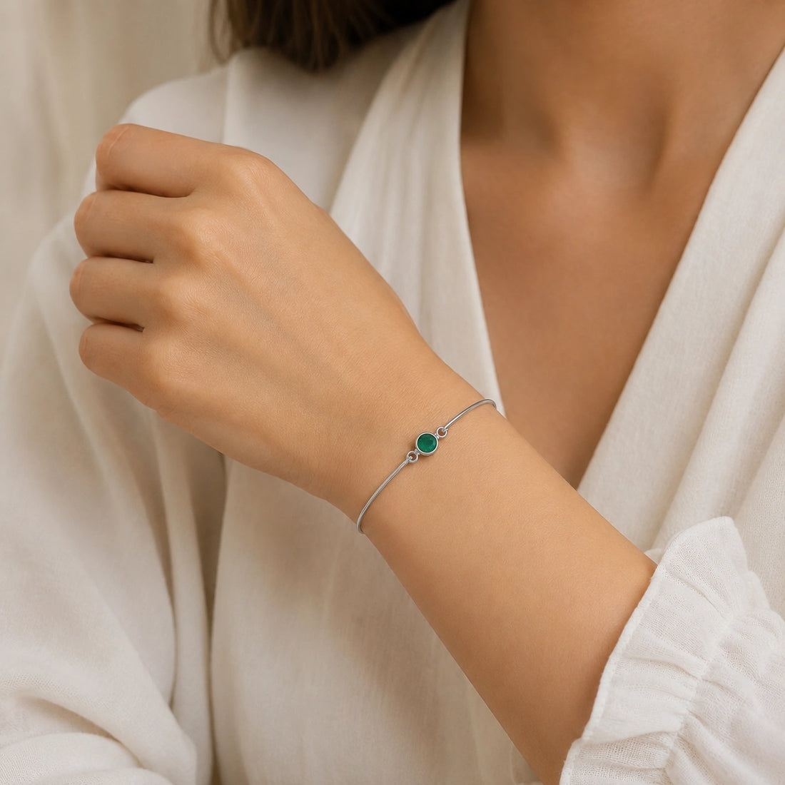 Gemstone_bracelet_in_gold_plated_silver_with_a_round_green_onyx_stone_at_front_angle_view_on_soft_fabric_background