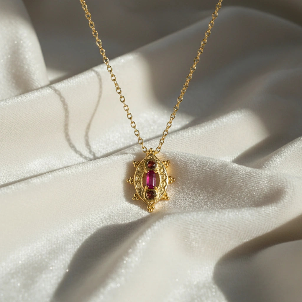 Gemstone-necklace-in-gold-plated-silver-with-pink-and-red-stones-in-front-angled-view-on-soft-silk-background