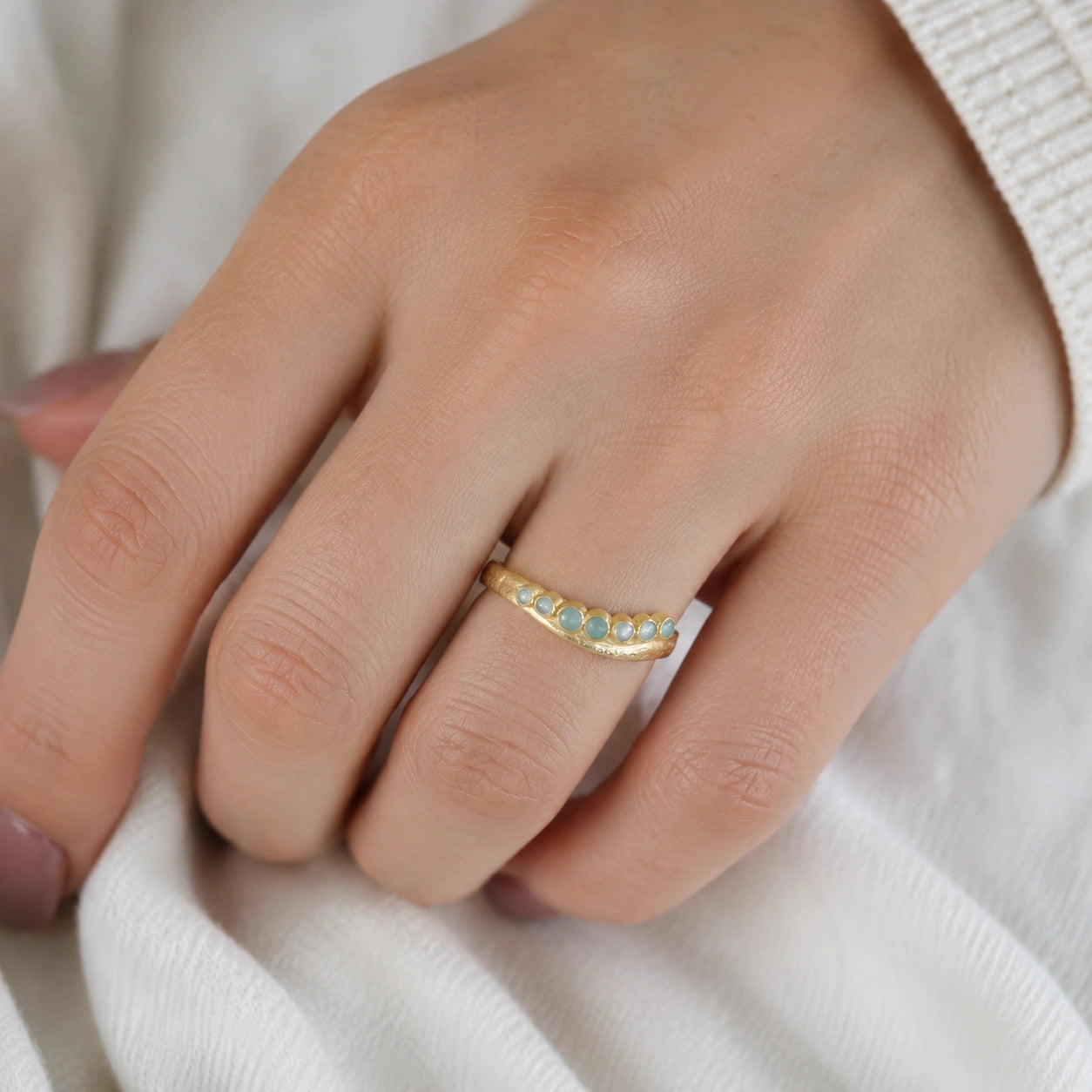 Gemstone_ring_in_gold_plated_silver_at_slightly_angled_featuring_amazonite_stones_in_a_curve_design_worn_by_a_model