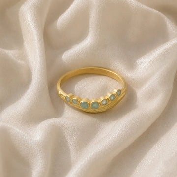 Gemstone_ring_in_gold_plated_silver_at_front_angle_featuring_amazonite_stones_in_a_curve_design_on_soft_fabric_background