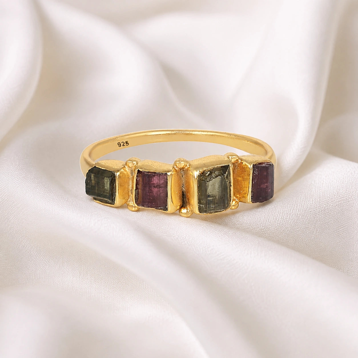 Gemstone_ring_with_tourmaline_stones_in_gold_plated_silver_at_front_angle_view_on_soft_fabric_background