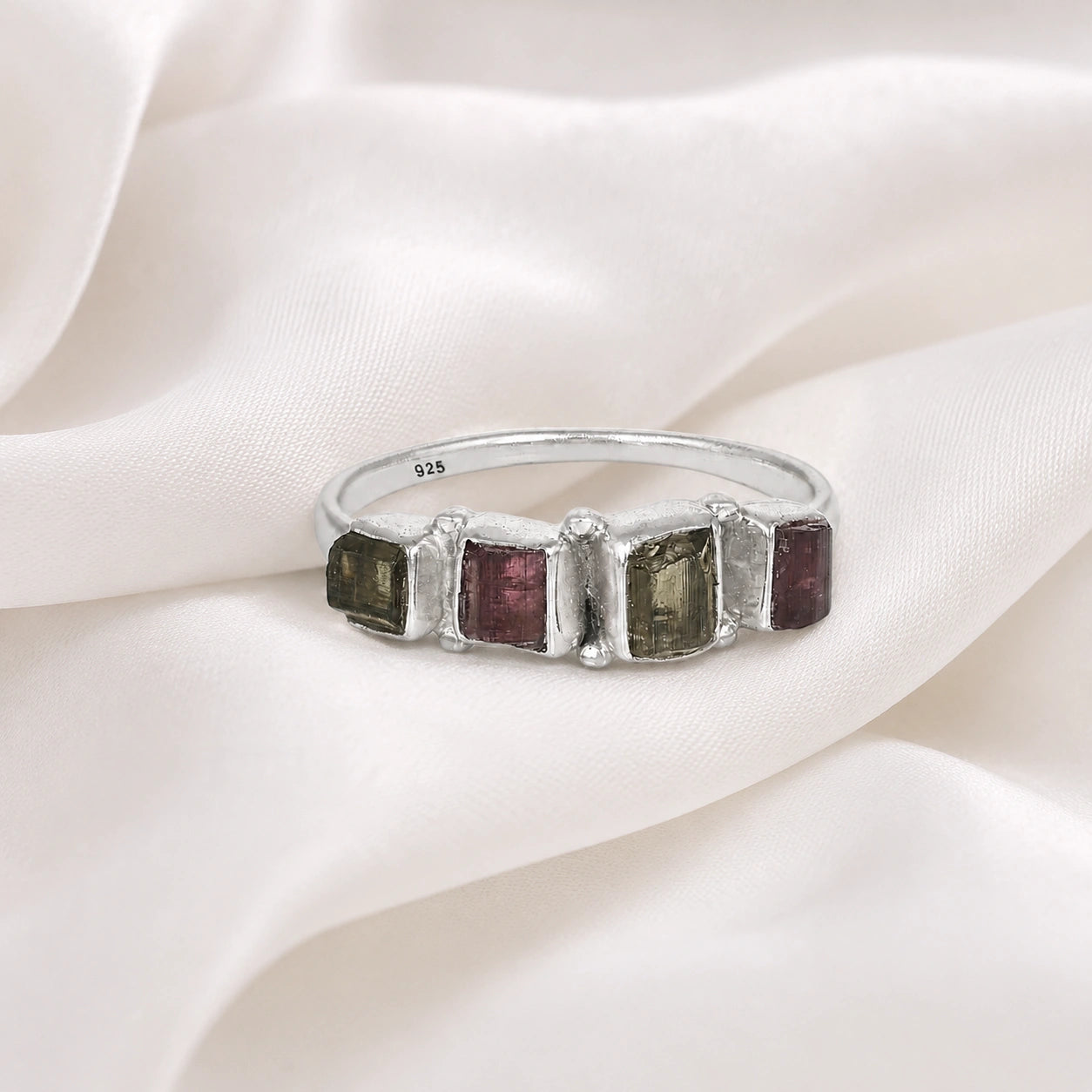Gemstone_ring_with_tourmaline_stones_in_sterling_silver_at_front_angle_view_on_soft_fabric_background