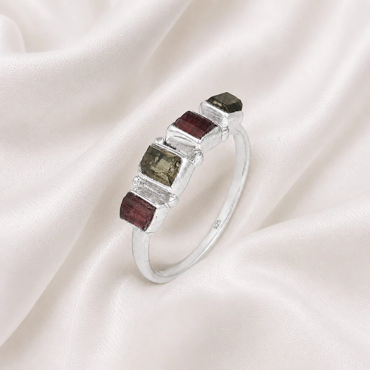 Gemstone_ring_with_tourmaline_stones_in_sterling_silver_at_slight_angle_view_on_soft_fabric_background