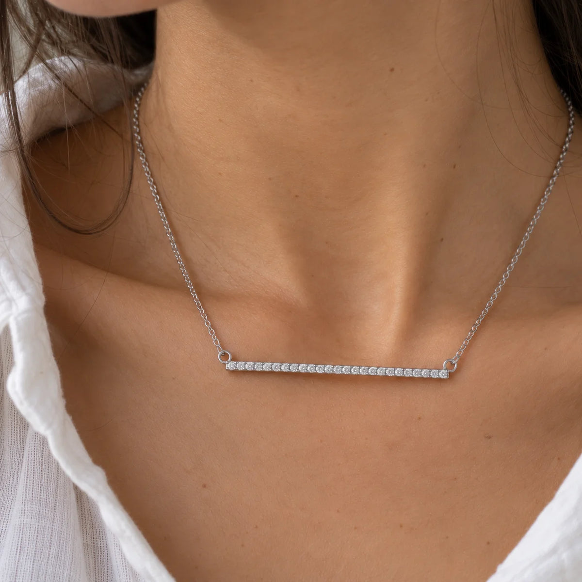 Gemstone_necklace_in_sterling_silver_in_a_bar_design_with_CZ_stones_at_front_angle_view_worn_by_a_model