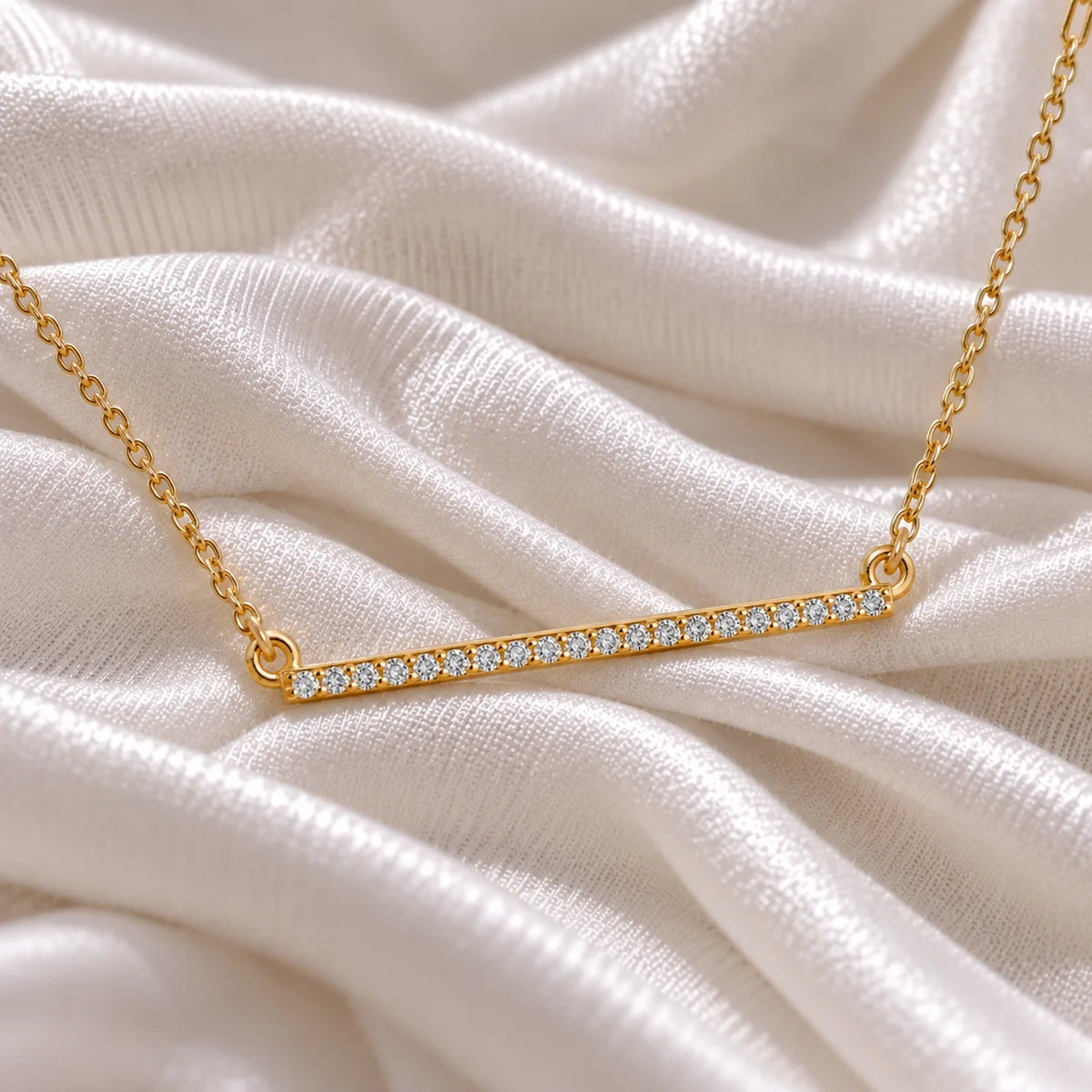 Gemstone_necklace_in_gold_plated_silver_in_a_bar_design_with_CZ_stones_at_side_angle_view_on_soft_fabric_background