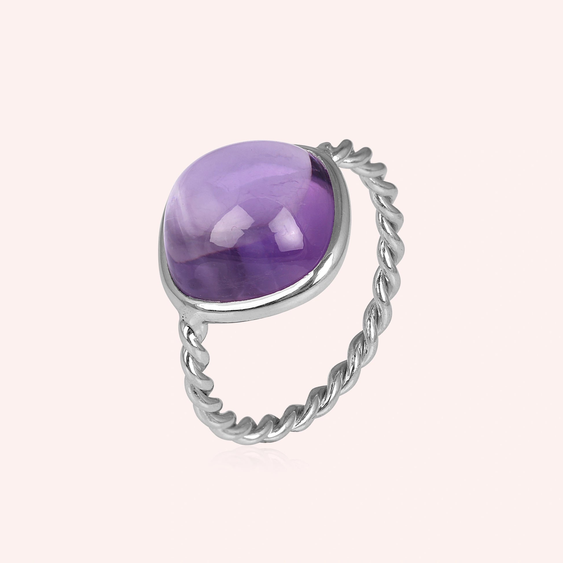 genuine amethyst ring cocktail ring shown at side angled view featuring purple stone with twisted silver band on pink background