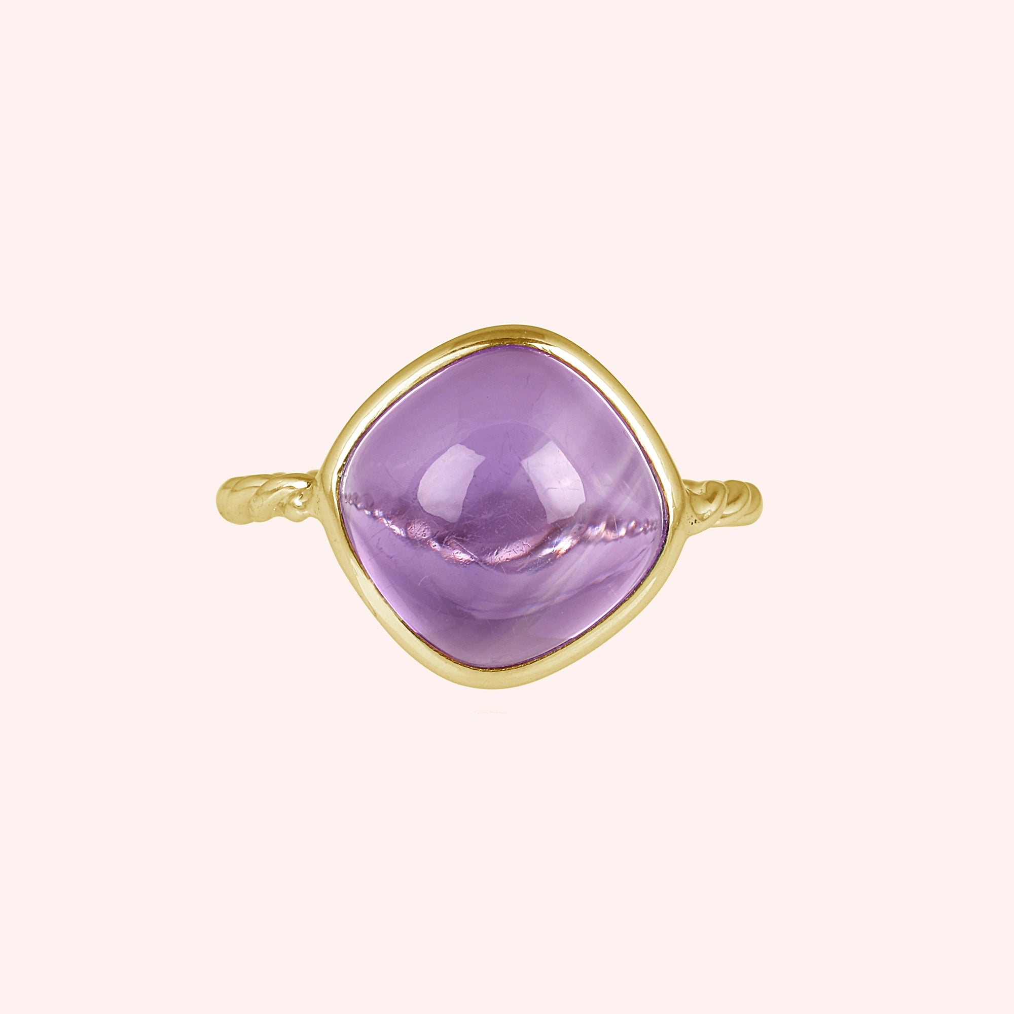 genuine amethyst ring cocktail ring shown at front angle view featuring purple stone with gold twisted band on a pink background
