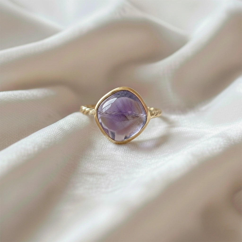 genuine amethyst ring cocktail ring shown at front angle view featuring purple stone with gold band on soft fabric background